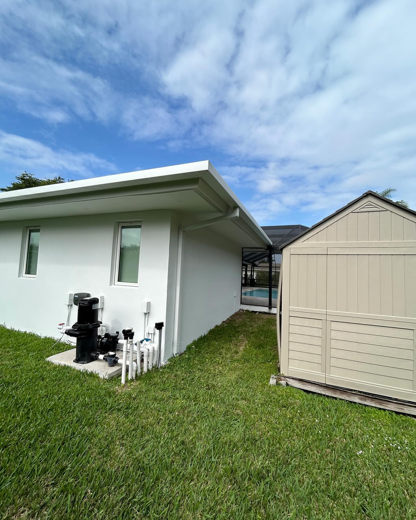 White seamless gutter along the eave of a single-story home beside a pool cage.