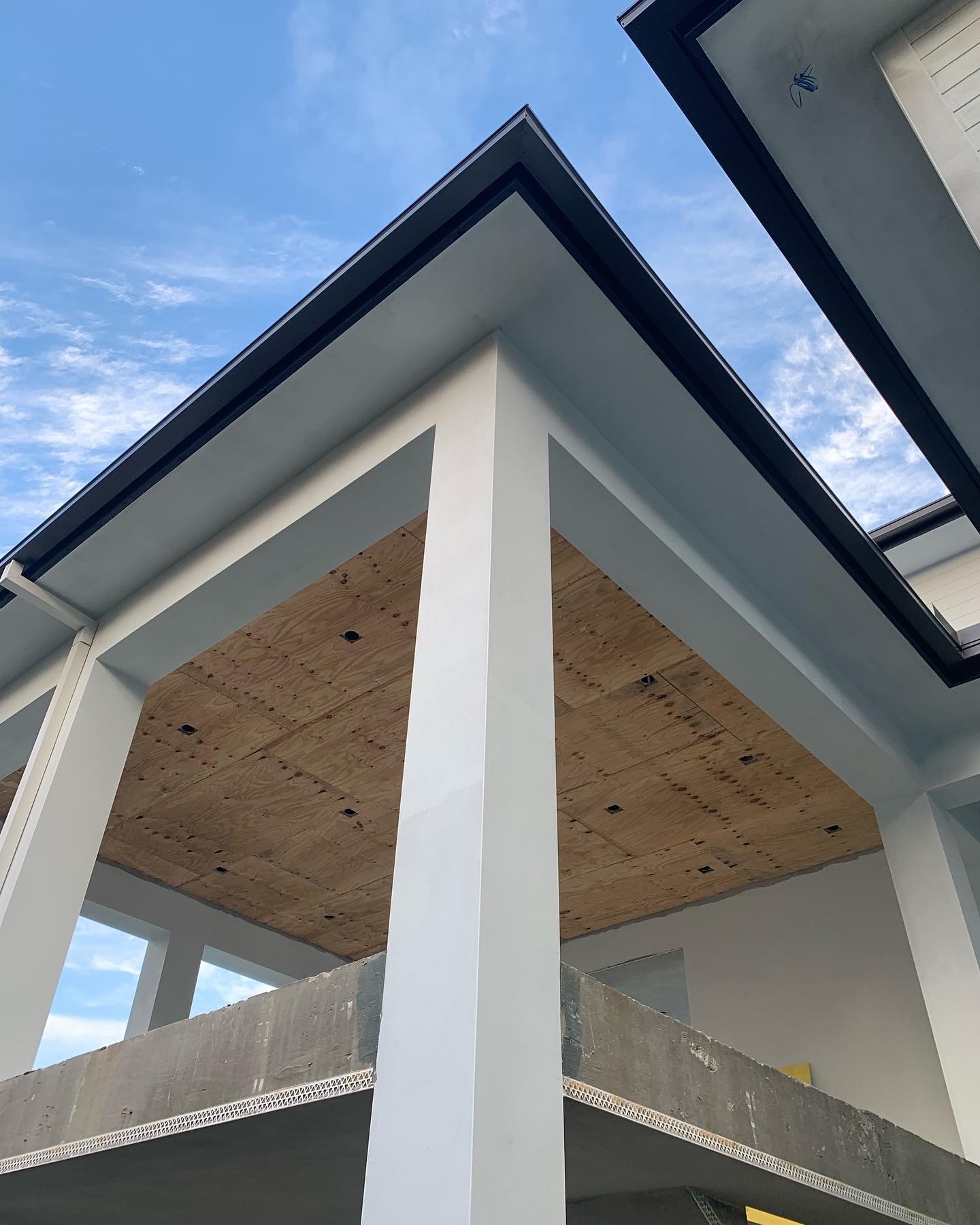 Low-angle eave detail with dark fascia trim against blue sky.