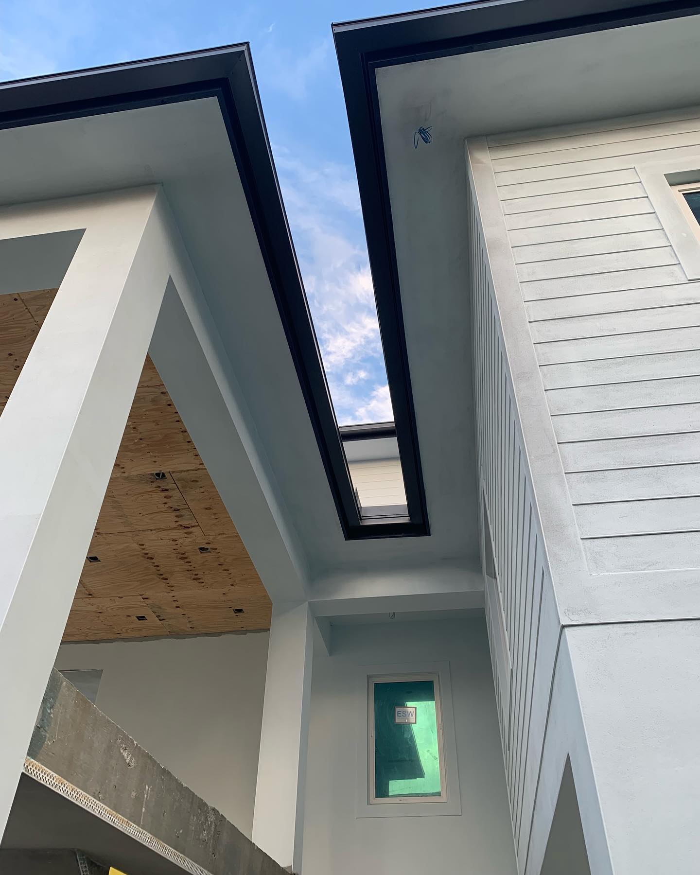 Twin roof eaves with black fascia trim framing blue sky.