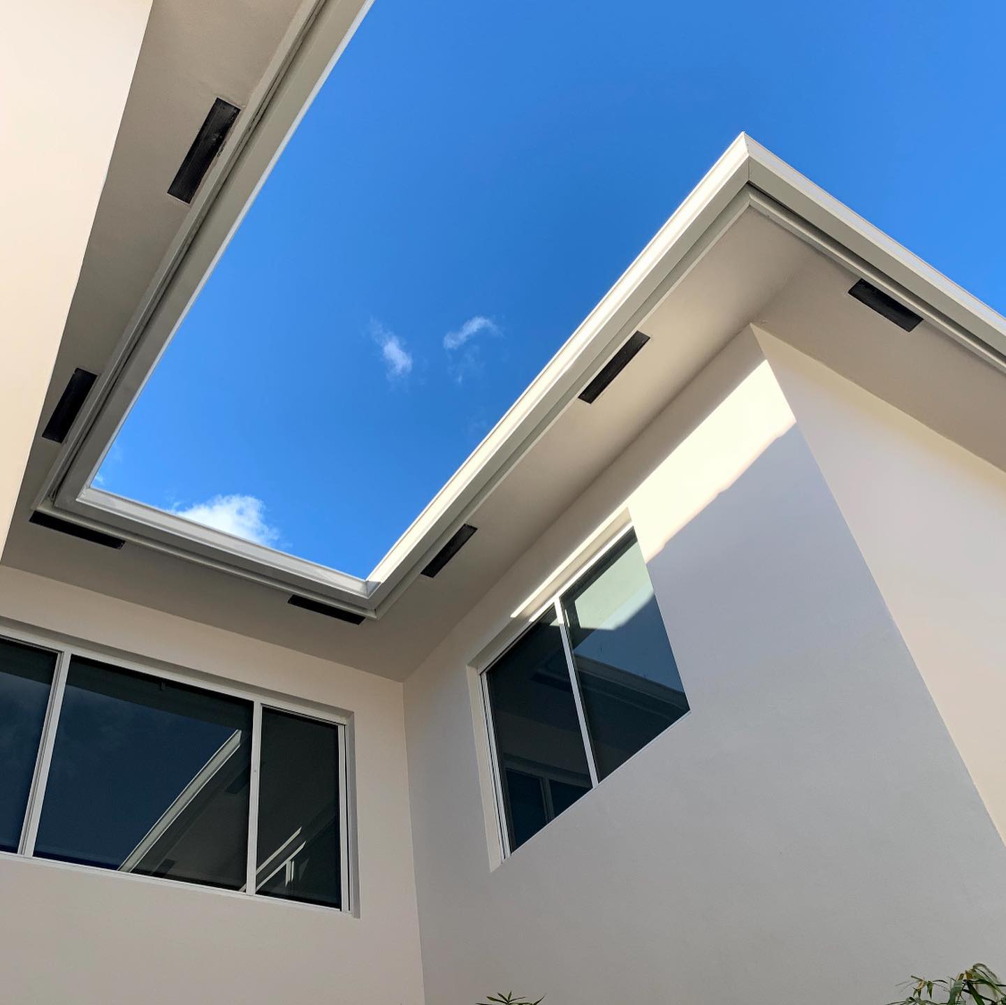 Upward view of white soffit, fascia and gutter lines framing open courtyard sky
