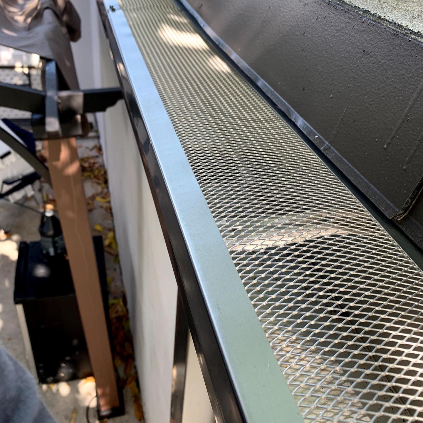 Close-up of mesh gutter guard installed over seamless gutter along shingle roof edge